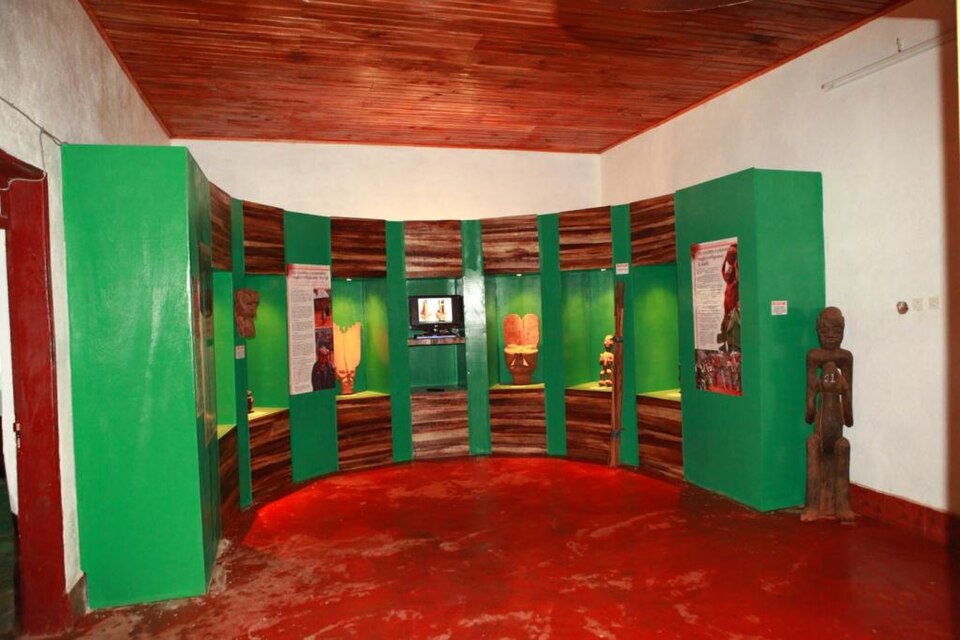 Salle du musée de Bamendjinda avec sculptures et panneaux d'exposition verts